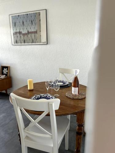 - une table en bois avec 2 chaises et une bouteille de vin dans l'établissement Appart T2 au Racou, à Le Racou