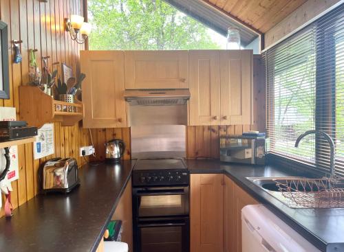 eine Küche mit Holzschränken und einem Herd mit Backofen in der Unterkunft Seil Log Cabin in Dalavich