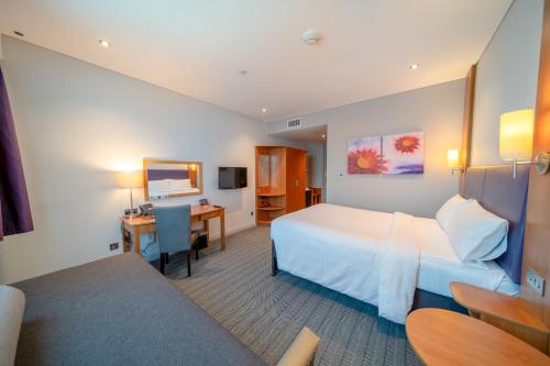 アブダビにあるPremier Inn Abu Dhabi Airport Business Parkのベッドとデスクが備わるホテルルームです。