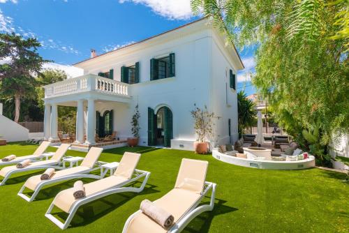 a group of lounge chairs on a lawn in front of a house at Villa De Los Leones in heart of Sitges by Beach and Town with A/C and Games in Sitges