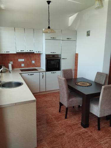 a kitchen with white cabinets and a table and chairs at Summer Beach House in Ulcinj