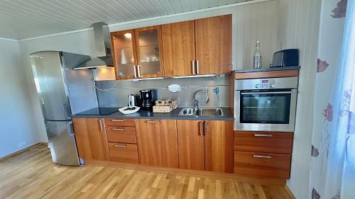 a kitchen with wooden cabinets and a sink and a refrigerator at Orcas View Vestresand Lofoten in Bøstad