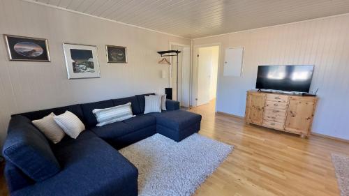 a living room with a blue couch and a flat screen tv at Orcas View Vestresand Lofoten in Bøstad