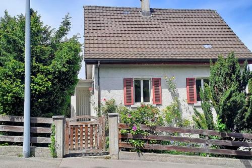a white house with red shutters and a wooden fence at Dein Haus für den Zürich-Trip! in Adliswil