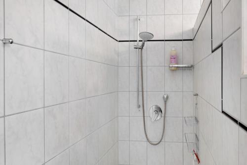 a white tiled shower with a shower head at Entenhaus in Hilgendorf