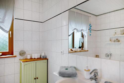 a white tiled bathroom with a sink and a mirror at Entenhaus in Hilgendorf