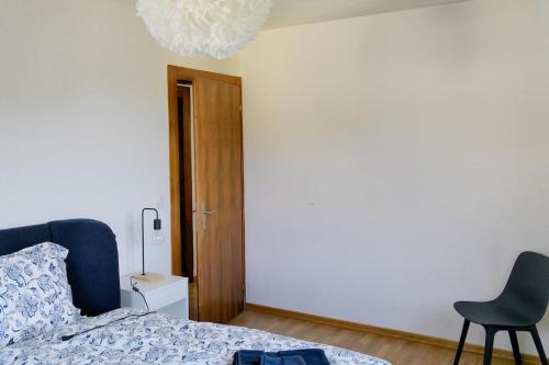 a bedroom with a bed and a chair and a chandelier at Dein Haus für den Zürich-Trip! in Adliswil