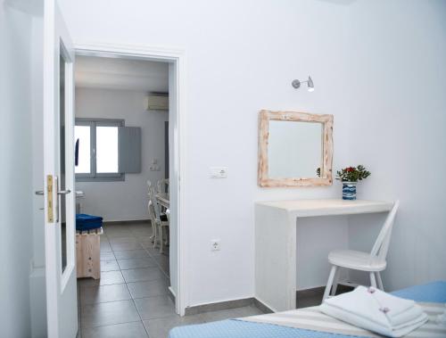 Habitación blanca con silla y espejo en The Last Sunbeam - Adults Only en Fira