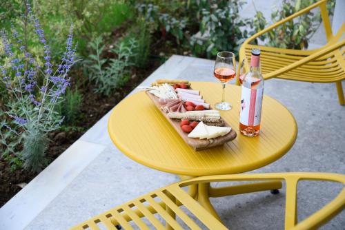 a yellow table with a plate of food and a bottle of wine at Falena Luxury Rooms in Kalyves Poligirou