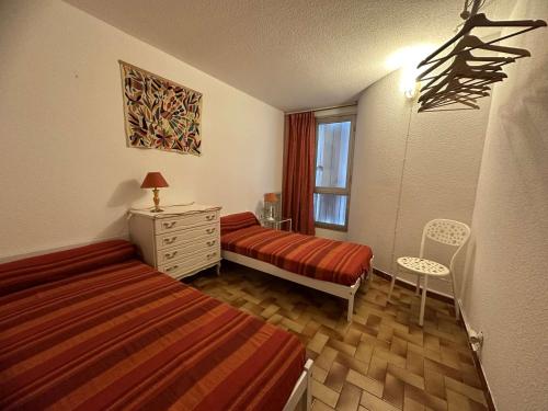 une chambre avec deux lits et une commode et une fenêtre dans l'établissement Spacieux T3 au Centre de La Grande-Motte, 500m Plage, Parking Privé - FR-1-328-139, à La Grande Motte