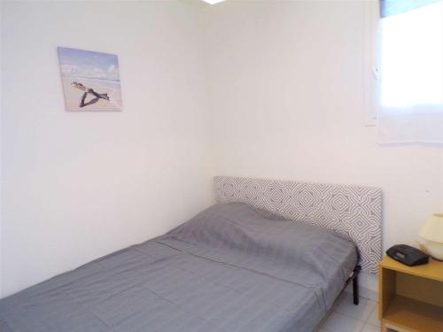 - une petite chambre avec un lit et une photo sur le mur dans l'établissement 2 Pièces avec Piscine, Proche Plage et Commerces, Quartier Calme avec Parking Privé - FR-1-328-145, à La Grande Motte