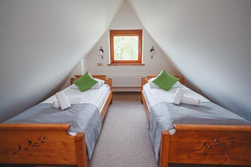 two twin beds in a attic room with a window at Hotel Eco Tatry Holiday& Spa in Kościelisko
