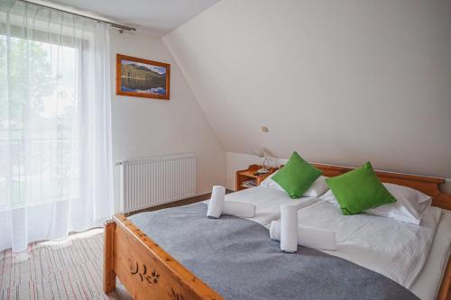 a bedroom with a bed with green and white pillows at Hotel Eco Tatry Holiday& Spa in Kościelisko