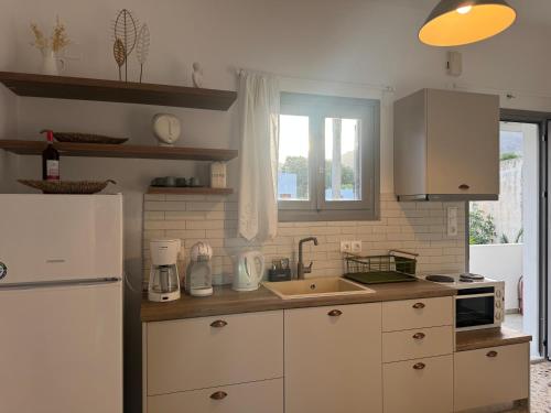 a kitchen with a white refrigerator and a sink at Akti Rooms And Studios in Livadion
