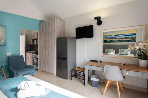 a small room with a bed and a desk and a kitchen at Beach Cabanas in Jeffreys Bay