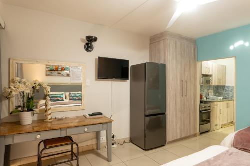 a kitchen with a stainless steel refrigerator and a desk at Beach Cabanas in Jeffreys Bay