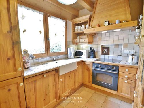 une cuisine avec des armoires en bois et un four à plaques de cuisson dans l'établissement Triplex 8 pers. en Chalet Traditionnel, Pied des Pistes, Terrasse, Balcon, Parking - FR-1-458-164, au Grand-Bornand