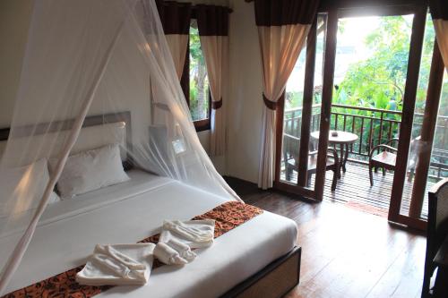 a bedroom with a bed with a canopy and a balcony at Lanta Happy Hill in Ko Lanta