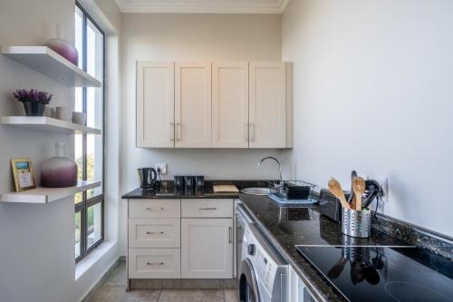 a kitchen with white cabinets and a black counter top at Knysna Views - Pezula Seashore - Sea-facing in Knysna