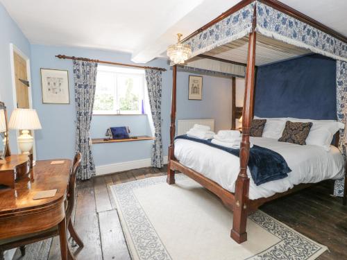 a bedroom with a canopy bed and a desk at Pentre Hall in Oswestry