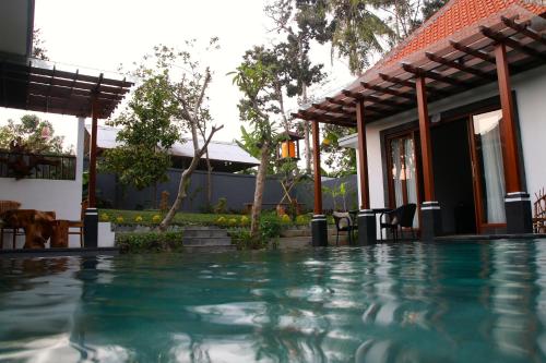a swimming pool in front of a house at Baruna Sari Villa in Ubud