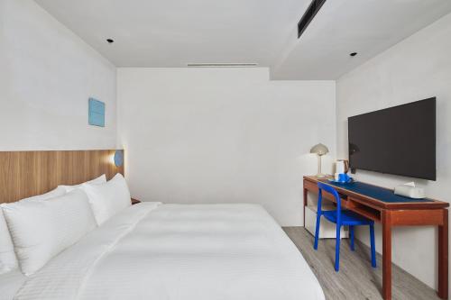a bedroom with a bed and a desk with a tv at The Blue by Just Inn in Taipei