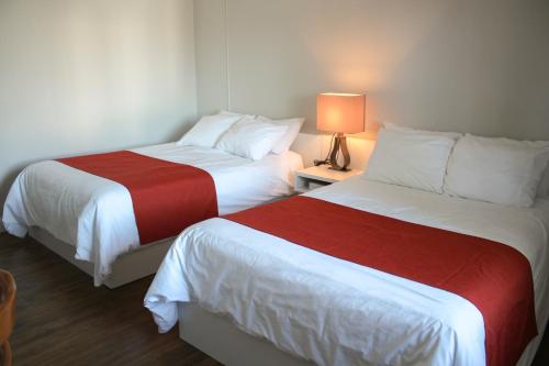 two beds in a hotel room with a lamp on a table at Auberge le Parasol in Saguenay