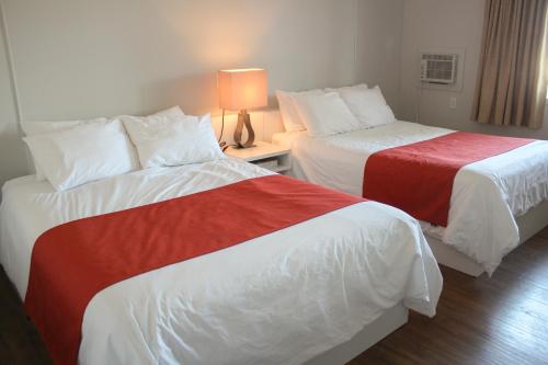 a hotel room with two beds with red and white sheets at Auberge le Parasol in Saguenay