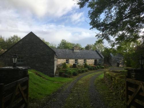 a stone house with a gravel road in front of it at Beautifully restored cottage nr Knock County Mayo in Kilkelly