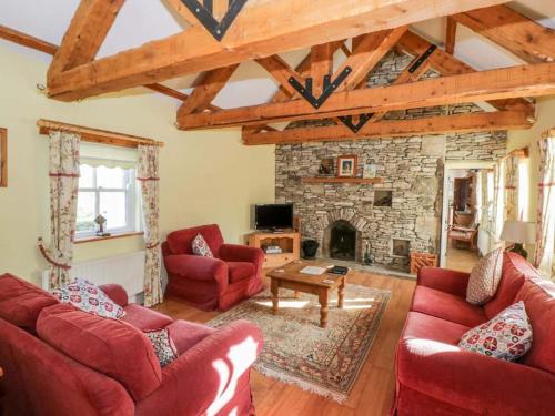 a living room with red couches and a stone fireplace at Beautifully restored cottage nr Knock County Mayo in Kilkelly