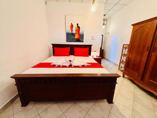 a bedroom with a large bed with red pillows at Bay Street in Beruwala