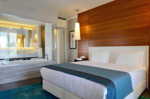 Sundance Suites Hotel في تورغوتري: غرفة نوم بسرير كبير وحوض استحمام