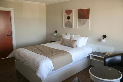 a bedroom with a large white bed with a chair at Auberge le Parasol in Saguenay