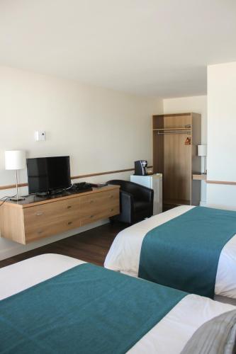 a hotel room with two beds and a flat screen tv at Auberge le Parasol in Saguenay