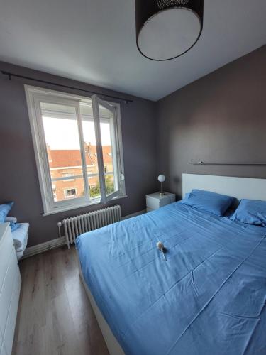 - une chambre avec un grand lit bleu et une fenêtre dans l'établissement Résidence Malouine 