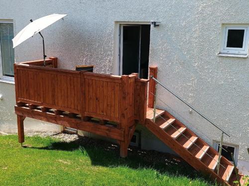 a wooden deck with an umbrella next to a building at Ferienwohnung zur Wacht in Viechtach