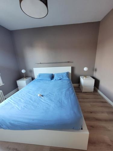 - une chambre avec un lit bleu et 2 tables de nuit dans l'établissement Résidence Malouine 