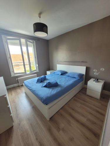 une chambre avec un lit avec des draps bleus et une fenêtre dans l'établissement Résidence Malouine 