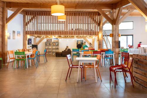 un restaurant avec des tables et des chaises dans une salle dans l'établissement Huttopia Les Châteaux, à Bracieux