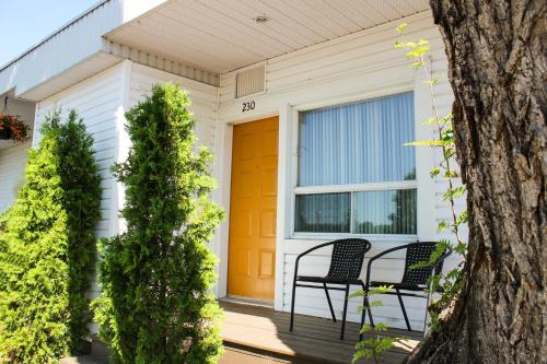 a porch of a house with two chairs and a orange door at Auberge le Parasol in Saguenay