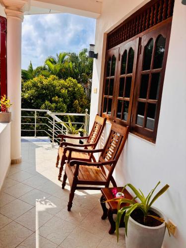 two wooden chairs sitting on a porch with a window at Bay Street in Beruwala