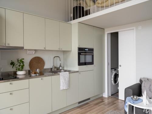 a white kitchen with white cabinets and a sink at Waterfront Cabins in Gothenburg