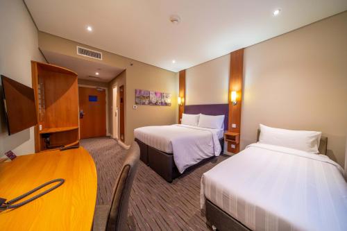 a hotel room with two beds and a television at Premier Inn Abu Dhabi Capital Centre in Abu Dhabi