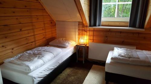 een kamer met 2 bedden in een hut met een raam bij De Rimboe en de Woeste Hoogte in Hoenderloo