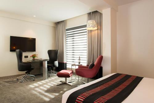 een hotelkamer met een bed, een bureau en stoelen bij Aauris in Calcutta