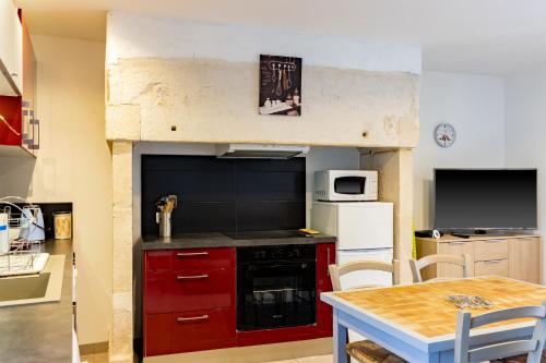 une cuisine avec des placards rouges, une cuisinière et une table dans l'établissement La Boutique 2 à 4 personnes, à Lacave