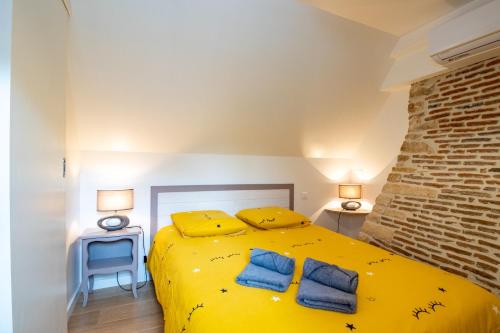 a bedroom with a yellow bed with two blue pillows at La Boutique 2 à 4 personnes in Lacave