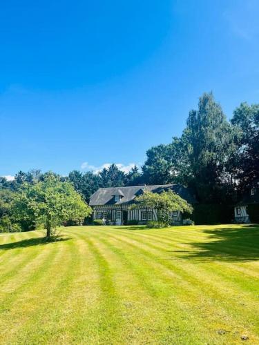 une grande cour herbeuse avec une grande maison dans l'établissement Splendide longère de charme - Collection Idylliq, à Conteville
