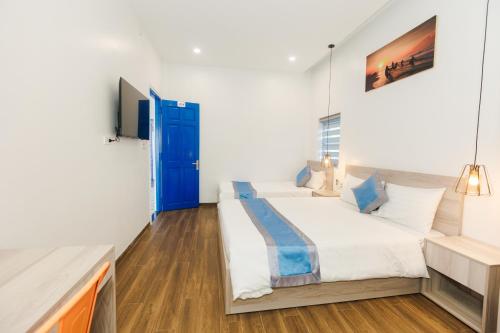 a bedroom with two beds and a blue door at Lee House Villa Tam Thanh in Tam Ky