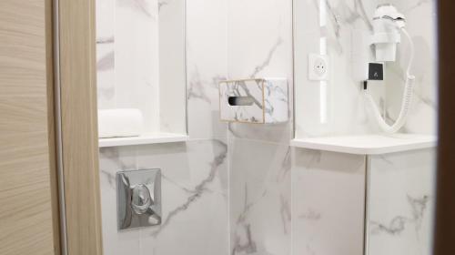 a bathroom with white marble walls and a phone at Geographotel Paris-Roissy CDG Airport in Le Mesnil-Amelot